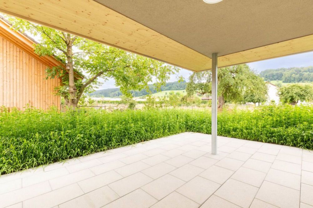 Nachhaltiges Wohnerlebnis aus Holz - Gedeckter Sitzplatz mit Aussicht ins Grüne