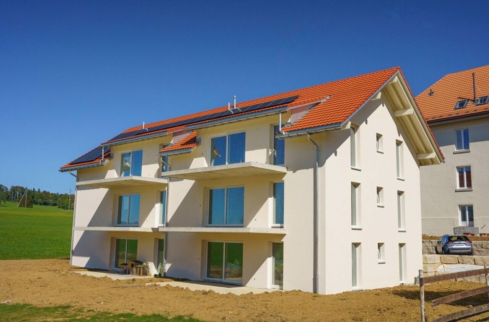 Exklusive und helle Apartments mit Ausrichtung - une maison blanche avec des panneaux solaires sur le toit / a white house with solar panels on the roof