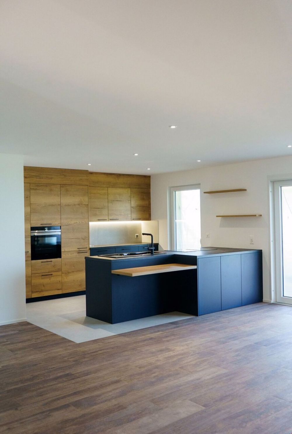 Exklusive und helle Apartments mit Ausrichtung - une cuisine moderne avec des armoires bleues et un îlot / a modern kitchen with blue cabinets and an island