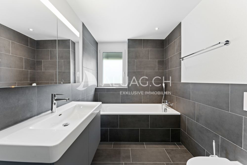 NEUBAUTRAUM 4.5 ZIMMER IM HERZEN DER NATUR - Weiteres Badezimmer mit Badewanne und zeitloser Gestaltung in stilvollen Grau- und Weisstönen