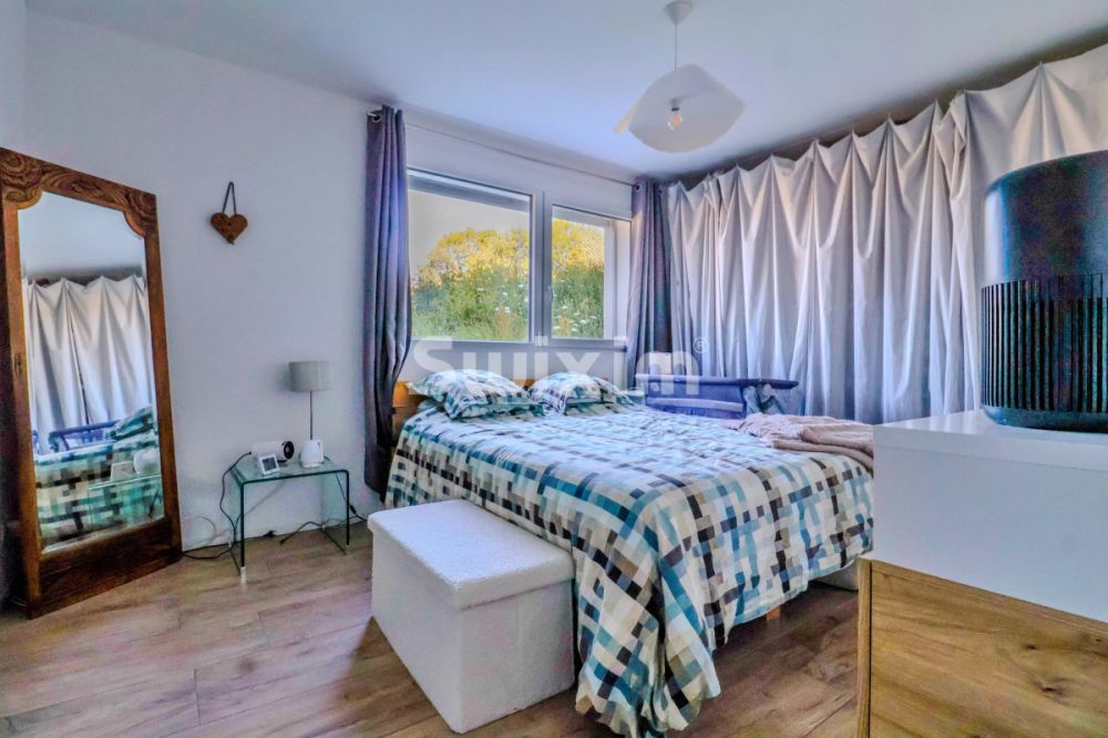 Exclusivité ! Vivez dans un village & confort :Appartement avec grande terrasse - Chambre lumineuse avec vue sur le jardin, équipée d'un grand lit et de rideaux élégants.
